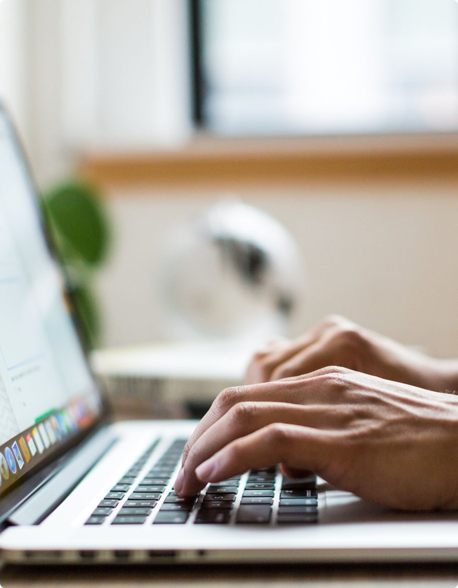 A close-up of hands typing on a laptop keyboard.