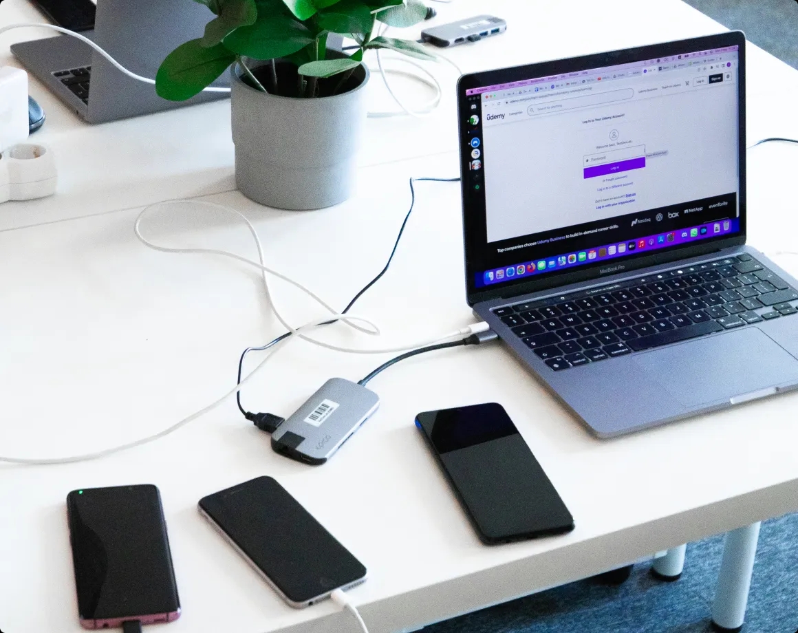 A desk with three mobile devices and a laptop.