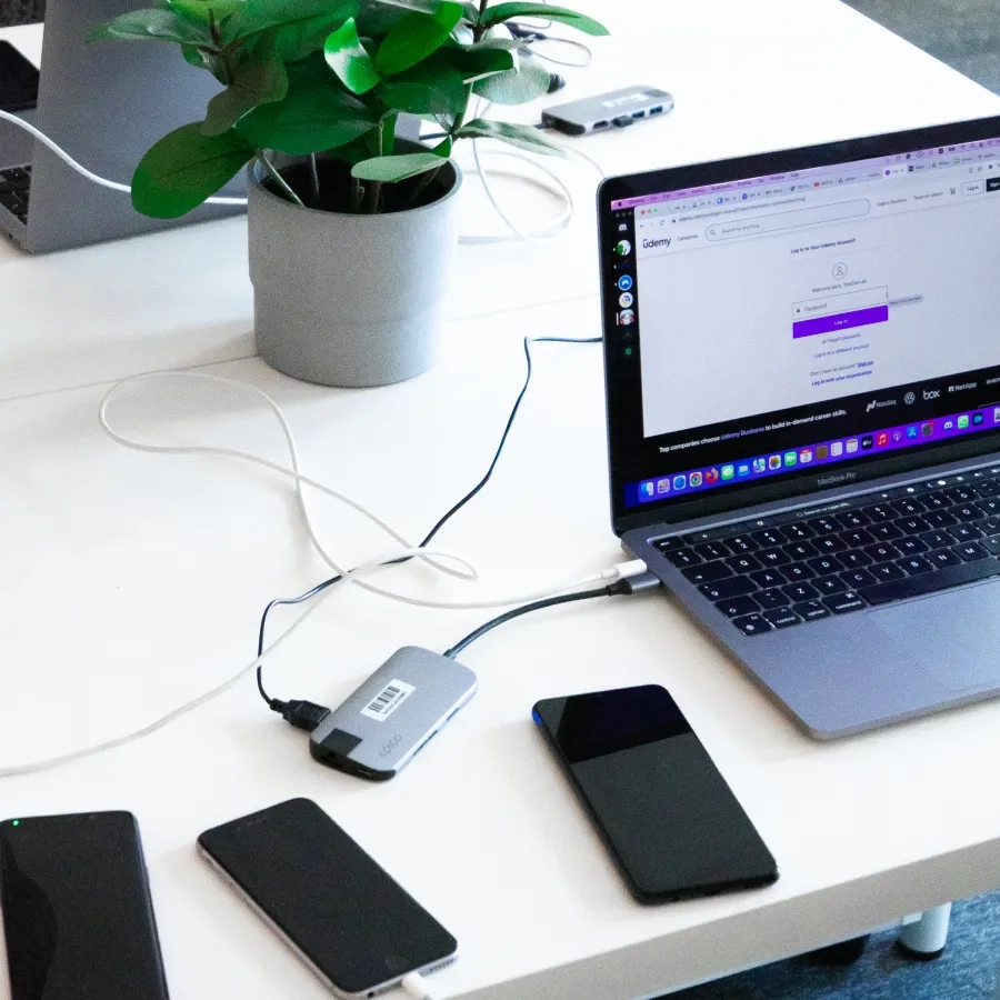A desk with multiple mobile phones and a laptop on top of it.