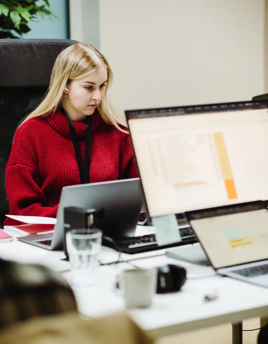 TestDevLab QA engineer working at desk with multiple screens