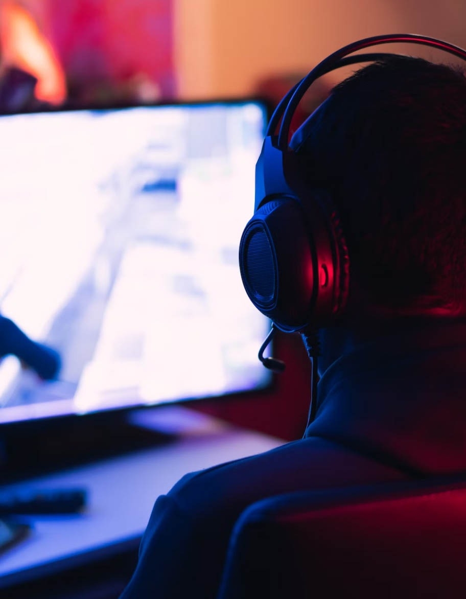 Engineer sitting at the desk in a dark environment, testing the game with the help of AI.