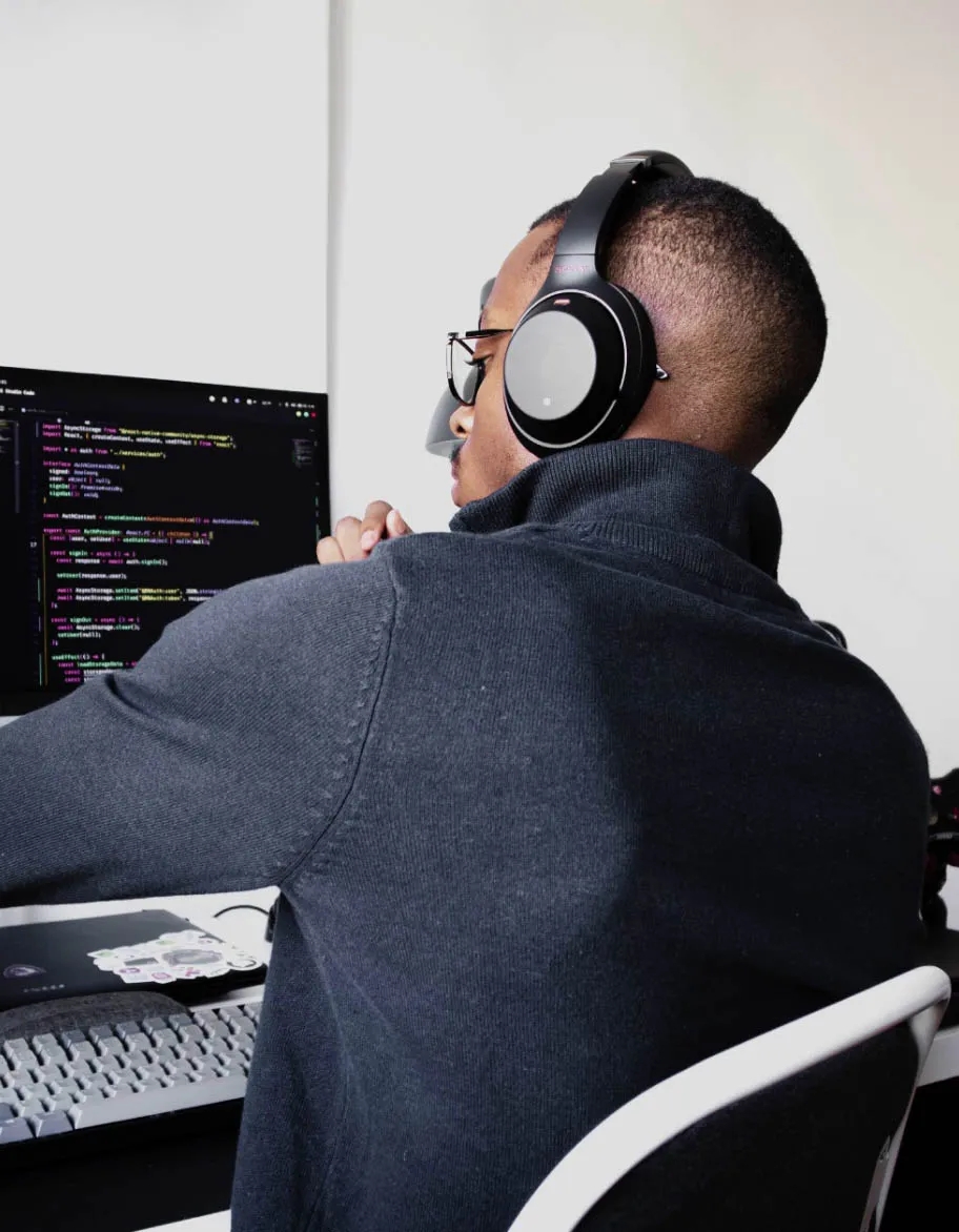 An engineer wearing headphones, sitting at the desk, and working on a test automation project.