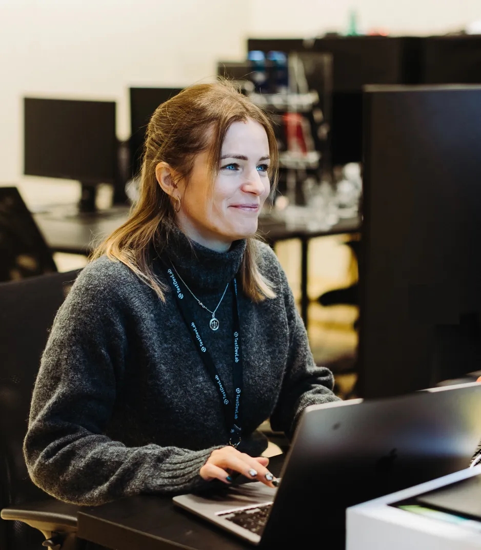 TestDevLab QA engineer working on AI testing at her desk
