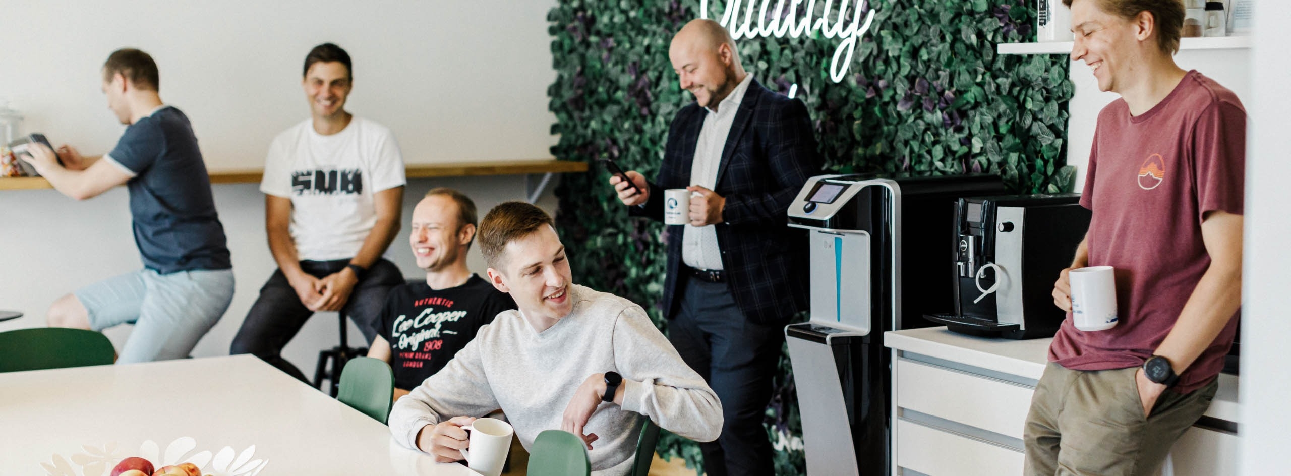 A group of software engineers enjoying a laugh in the office kitchen.