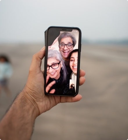 A close-up of a hand holding a mobile phone displaying a group video call.