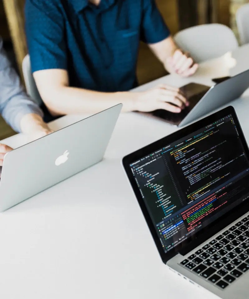 QA engineers collaborating at a desk with laptops