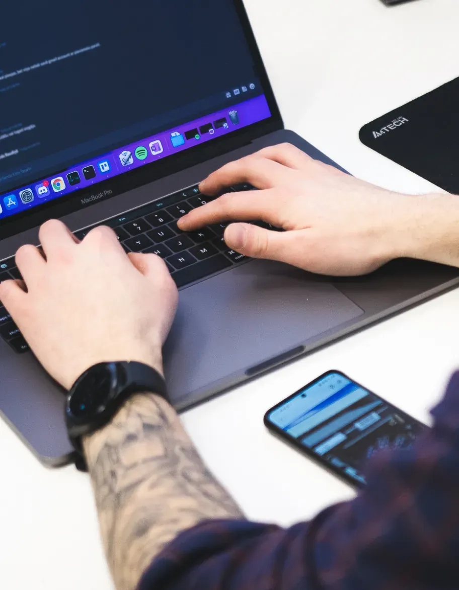 A laptop placed on the desk, with hands on the keyboard