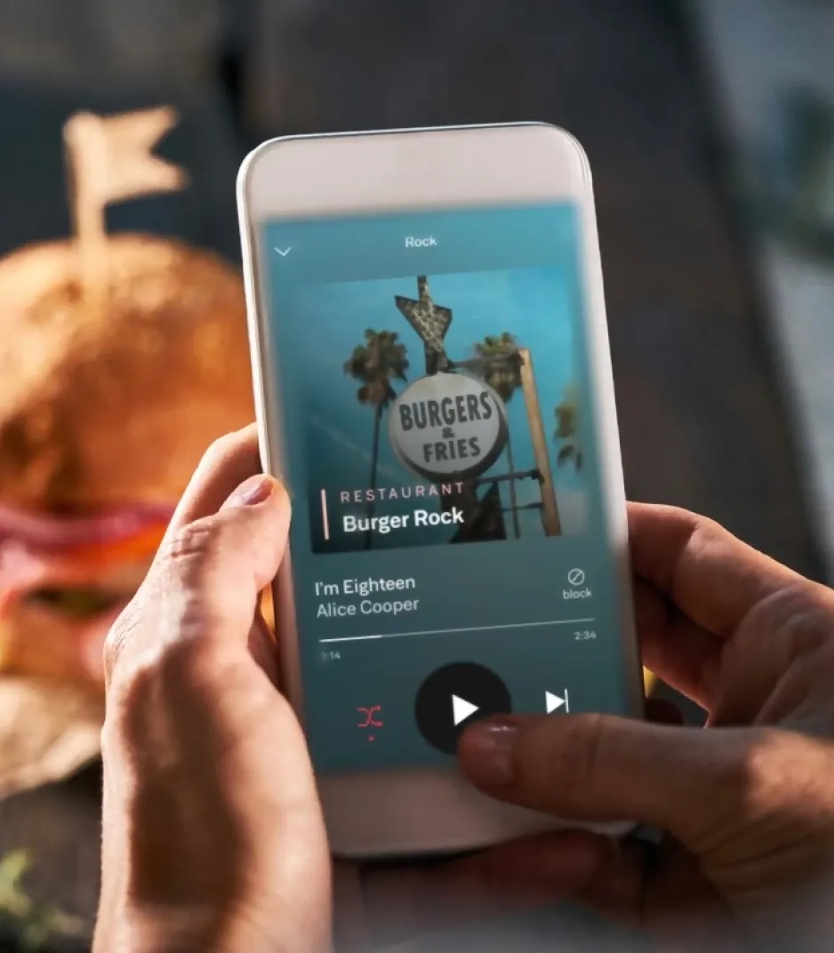 Close-up of a hand tapping the play button on a music streaming app.