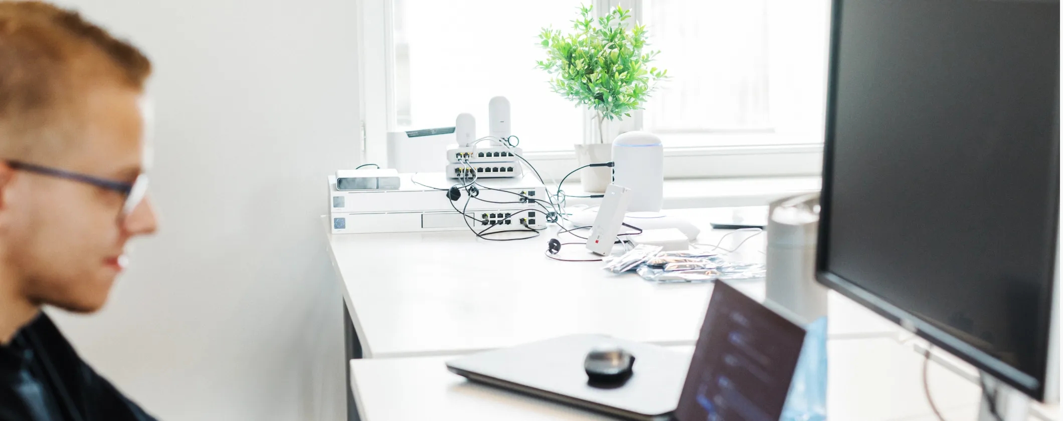 A network engineer sitting at a desk and working on a laptop computer.