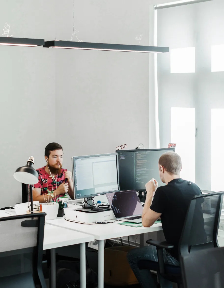An office space with two QA engineers sitting at their desks, working with computers.