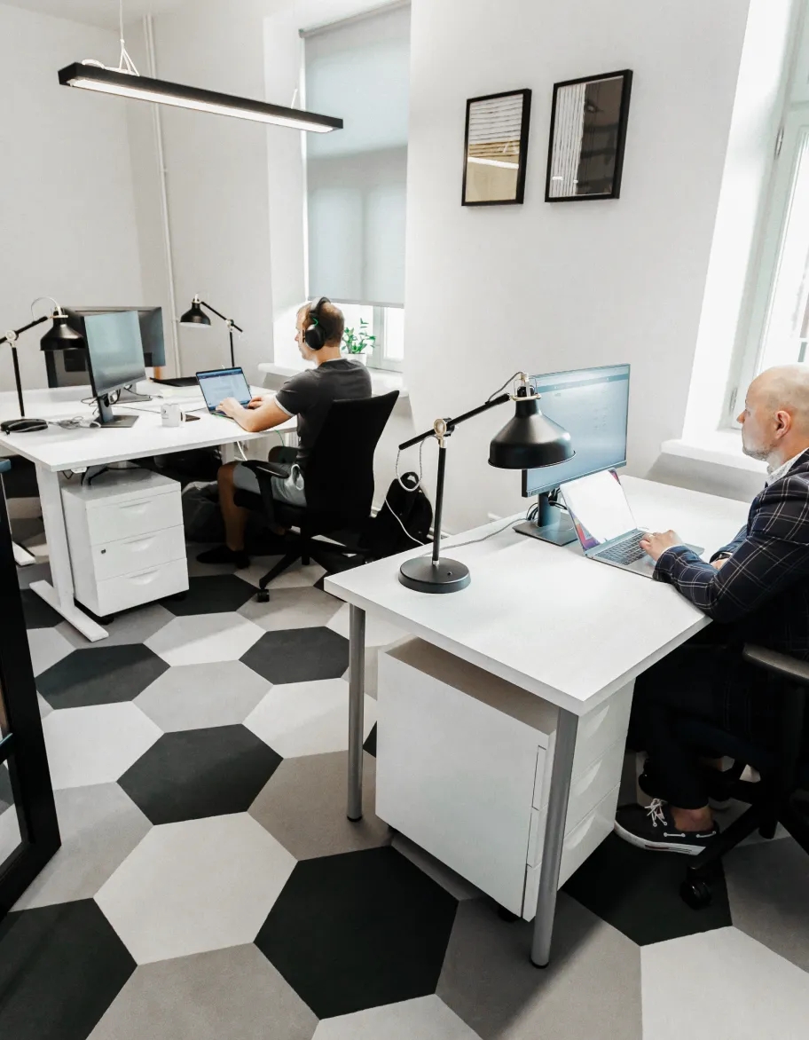 An open office space with two QA engineers sitting at their desks and working on computers.