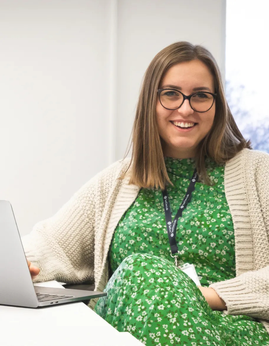 A person sitting at a desk and smiling at the camera.