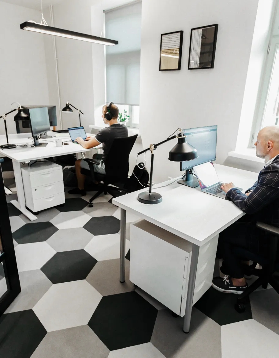 Ein offener Büroraum mit zwei QA-Engineers, die an ihren Schreibtischen sitzen und an Computern arbeiten.