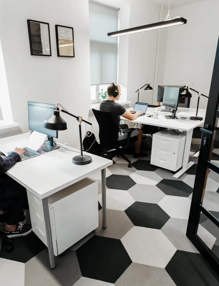Ingeniero de QA sentado en un escritorio en una oficina, trabajando en una laptop