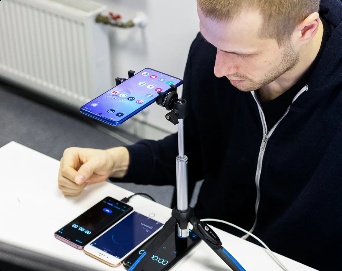 QA engineer watching 3 devices placed on a desk.