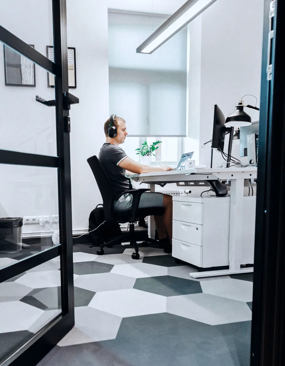 QA engineer wearing headphones, sitting at the desk in the office and working with computer.