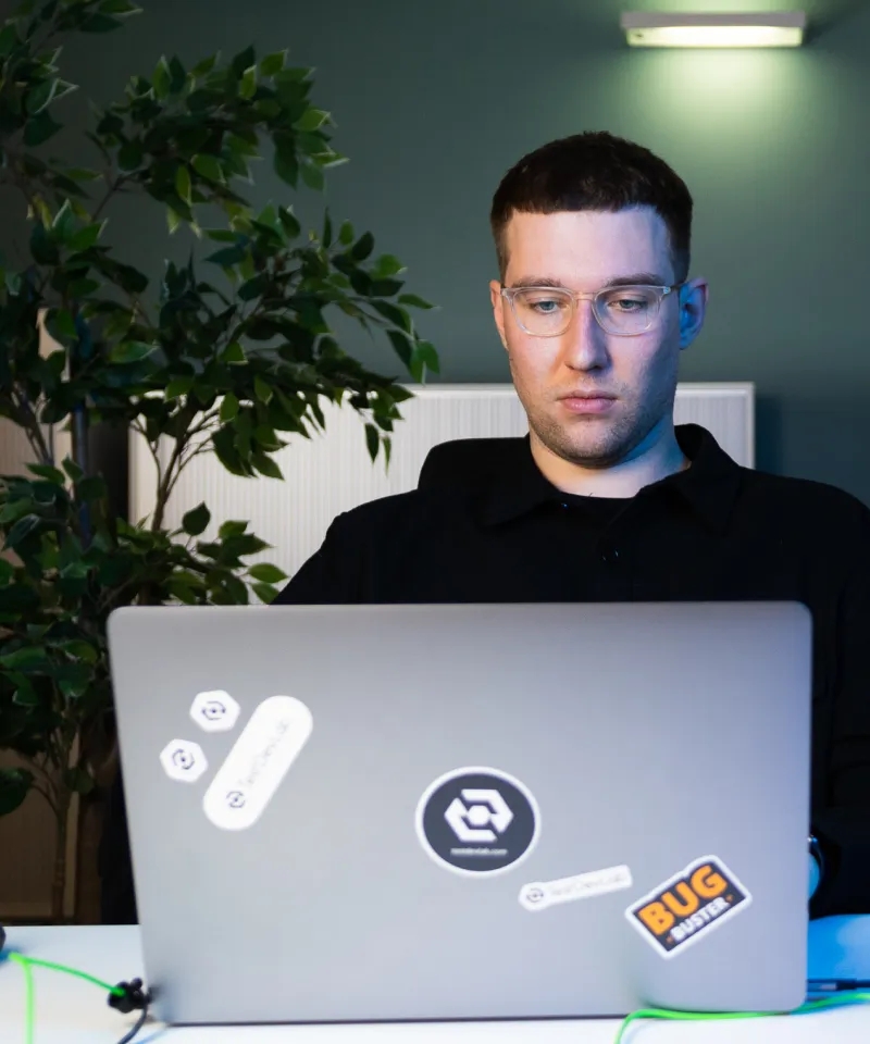 QA Engineer sitting at the desk, using a laptop.