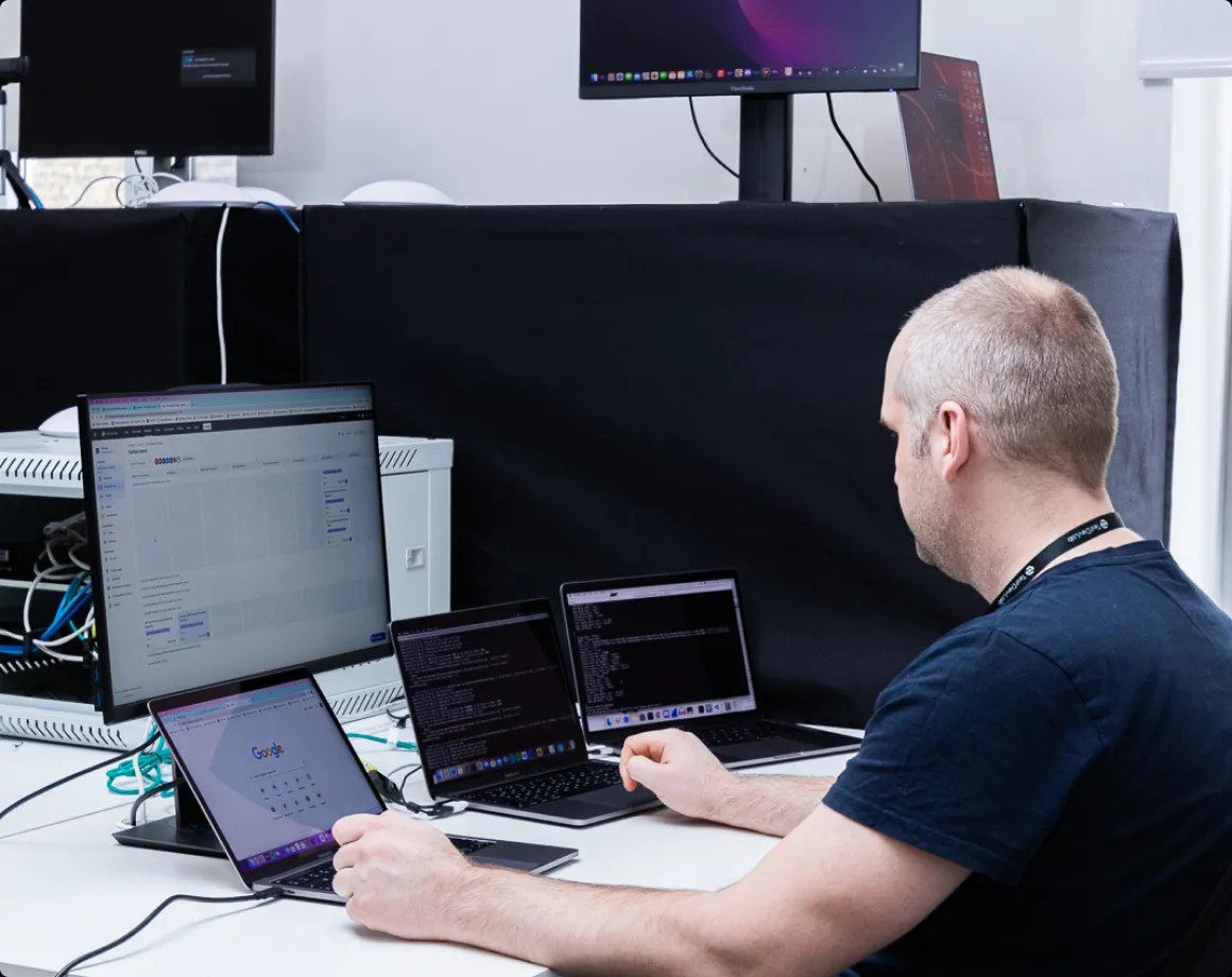 A QA engineer working with multiple laptops on a desk.