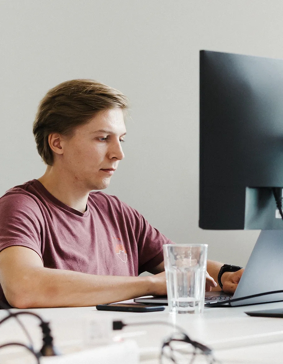 Two QA engineers, where one is pointing at the monitor, but the other is listening.