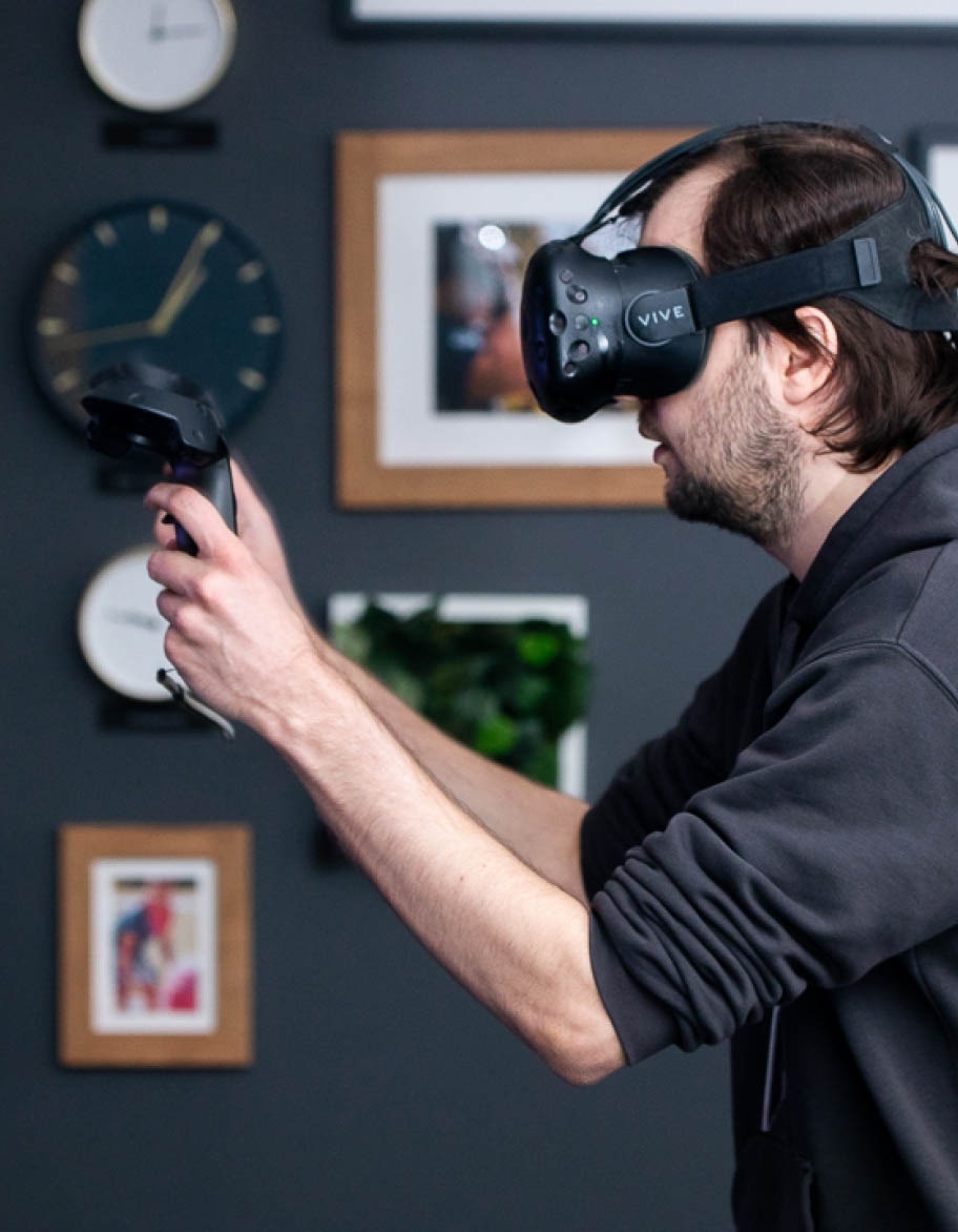 QA engineer wearing a VR headset and holding VR controllers in both hands while testing a VR solution.