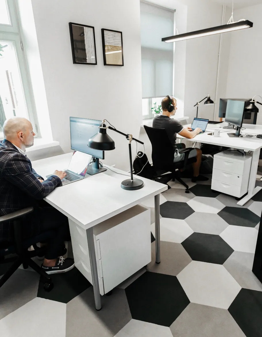 Ein offener Raum mit zwei QA-Ingenieuren, die an Schreibtischen sitzen und mit ihren Laptops arbeiten.