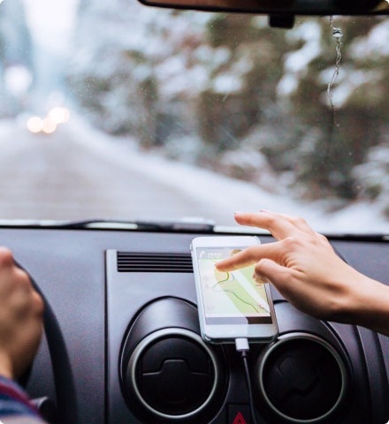 A person in a vehicle navigating a map on a mobile phone.