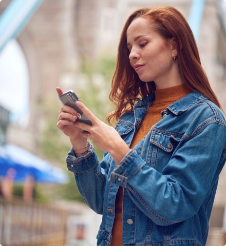 A woman holding and looking at a mobile phone.