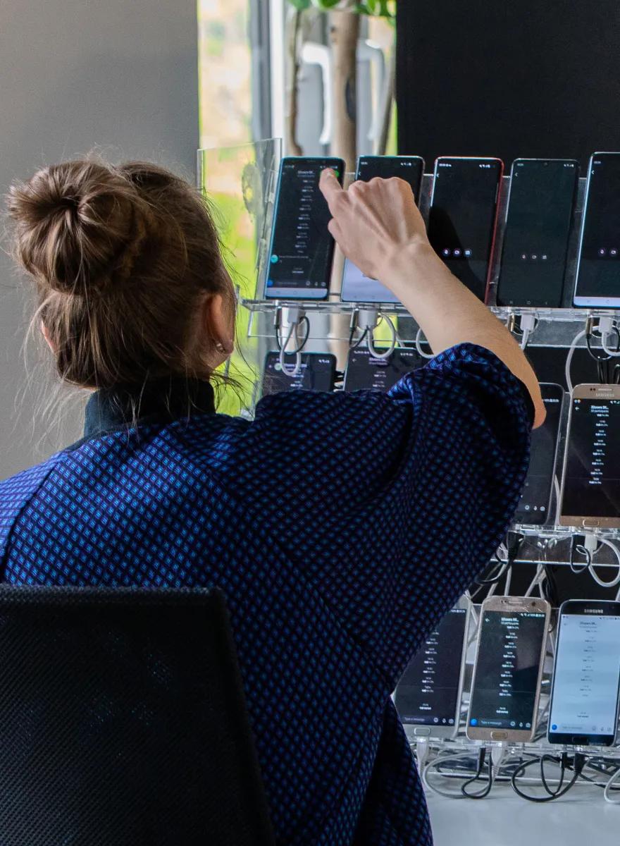 Ein TestDevLab-Ingenieur arbeitet an einem Rack mit echten mobilen Testgeräten