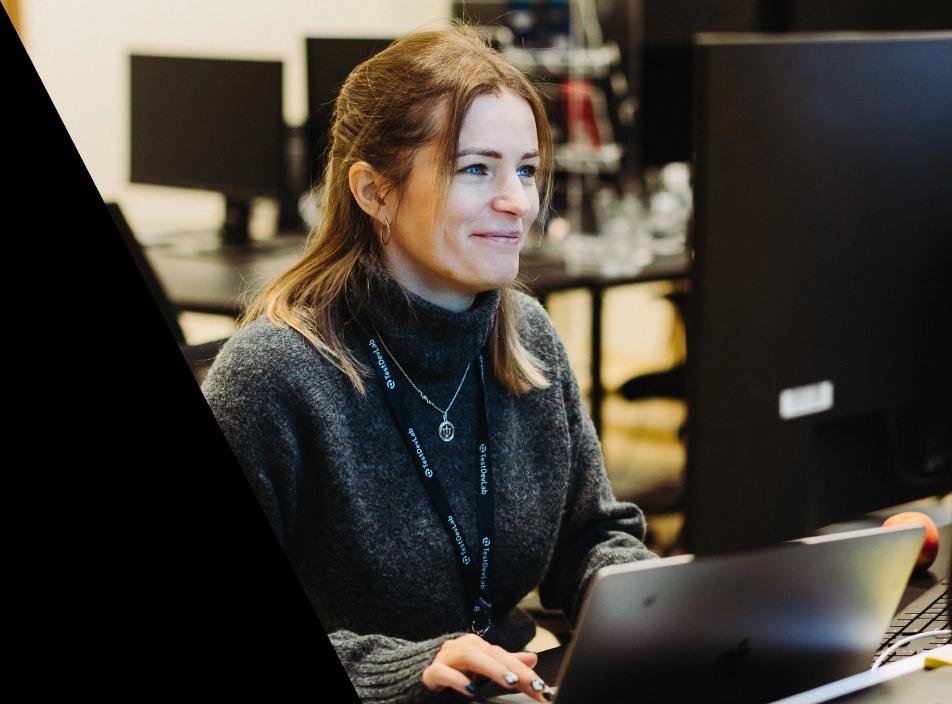 A woman looking at the external monitor placed on her desk.