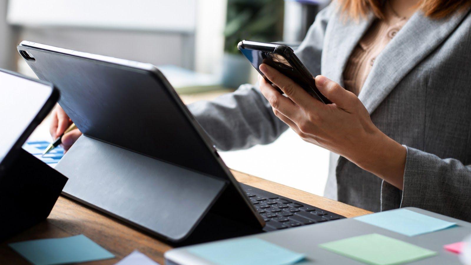 Woman working with a smartphone and tablet at her desk
