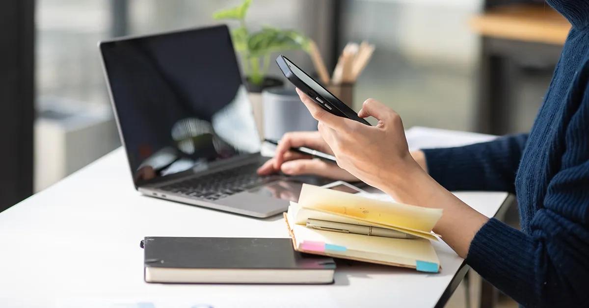 Woman working on her desk, holding a phone