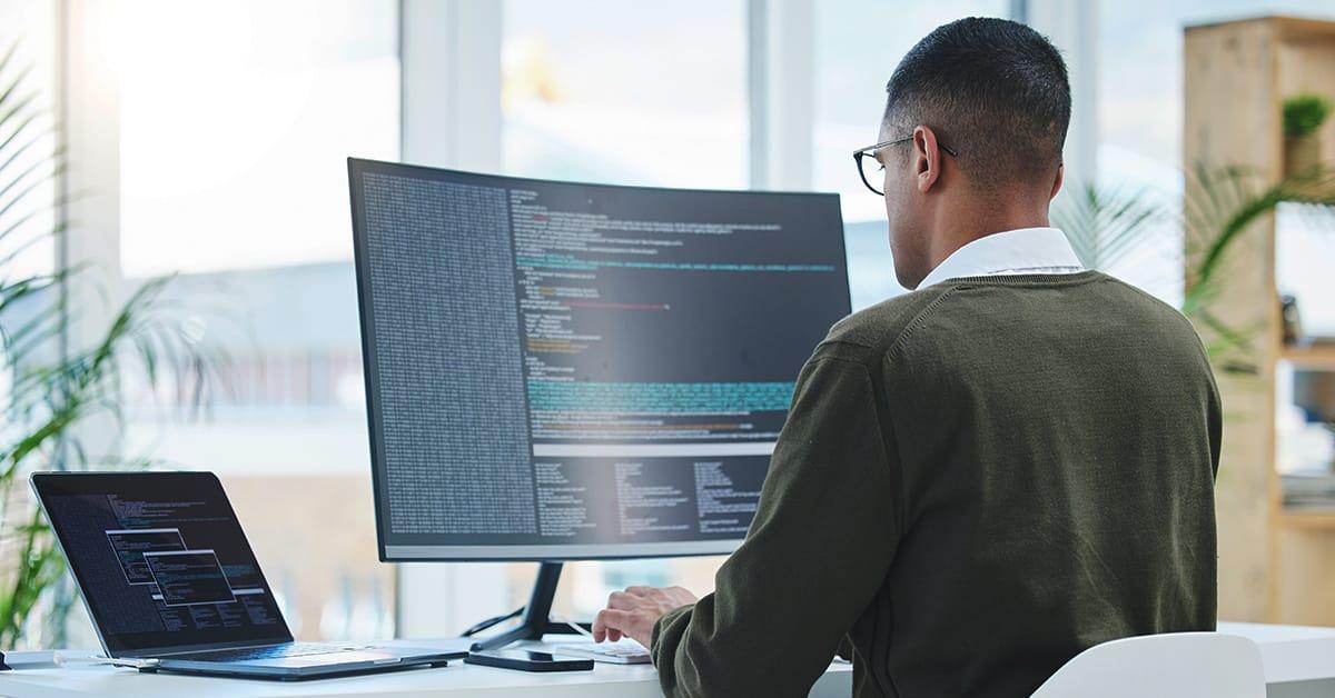 QA engineer sitting at a desk, facing and working on a desktop computer