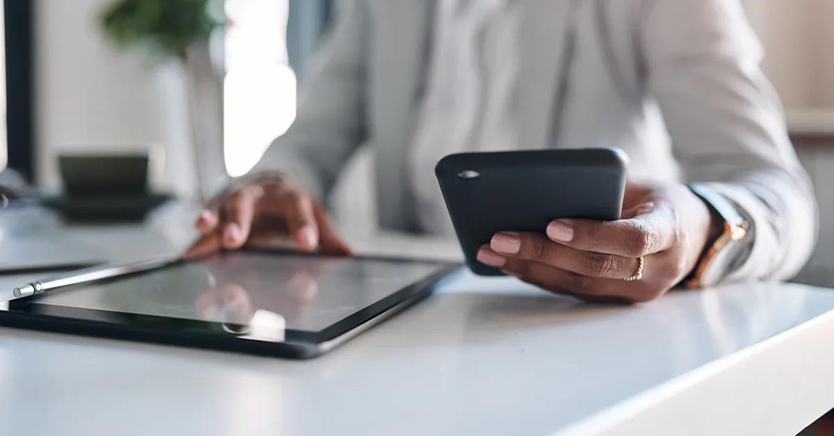 Woman holding a smartphone and working on a tablet