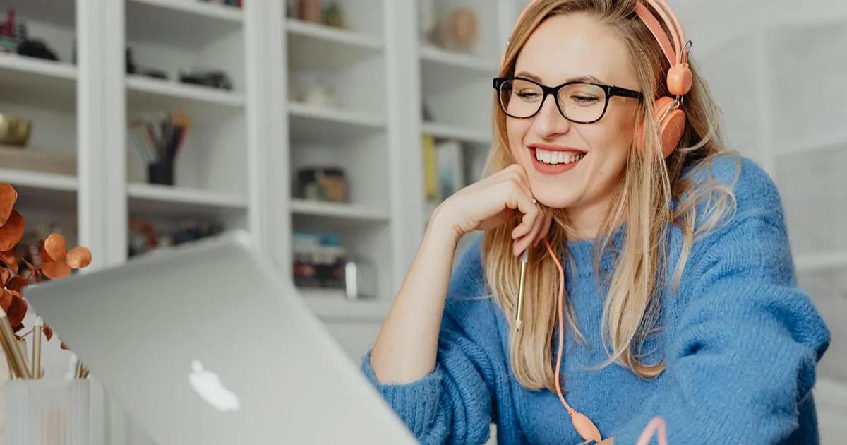 Woman wearing headphones and smiling while on a call on a laptop