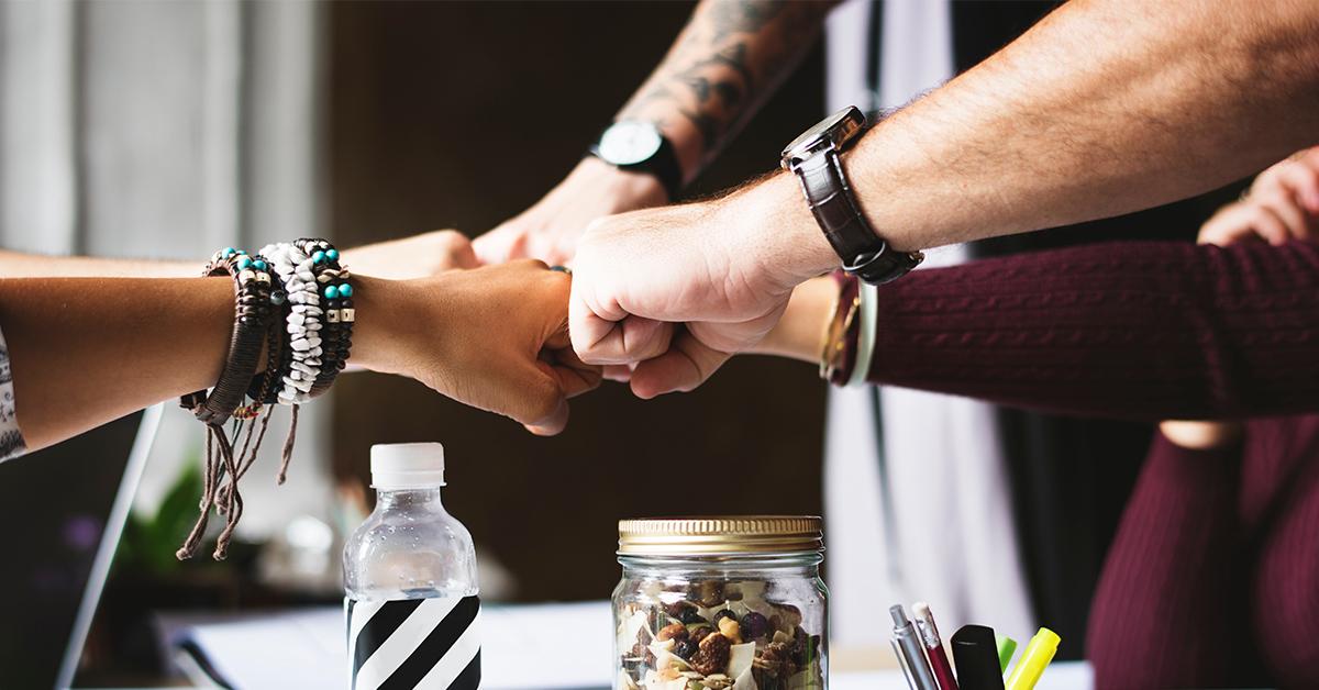 Group of people bringing their hands together as sign of teamwork