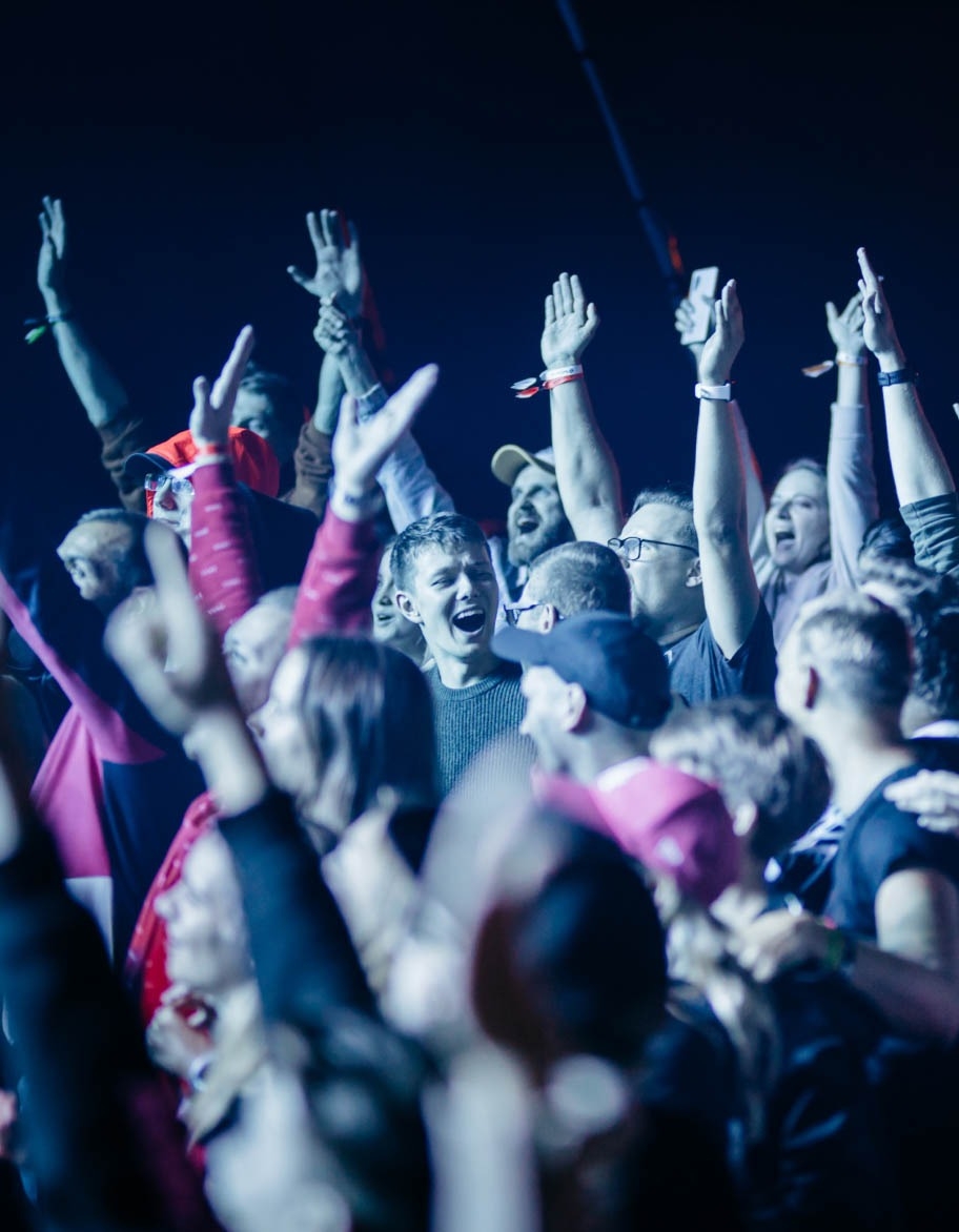 En gjeng mennesker danser med hendene opp i luften.