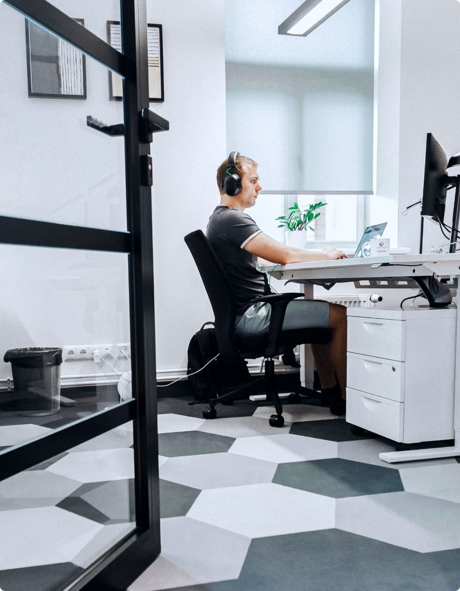 En QA-ingeniør sidder ved et skrivebord med hovedtelefoner og tester en kommunikationsapp.