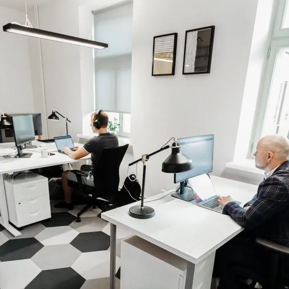 Åpent kontorlandskap med to QA-ingeniører som sitter ved skrivebordene sine.