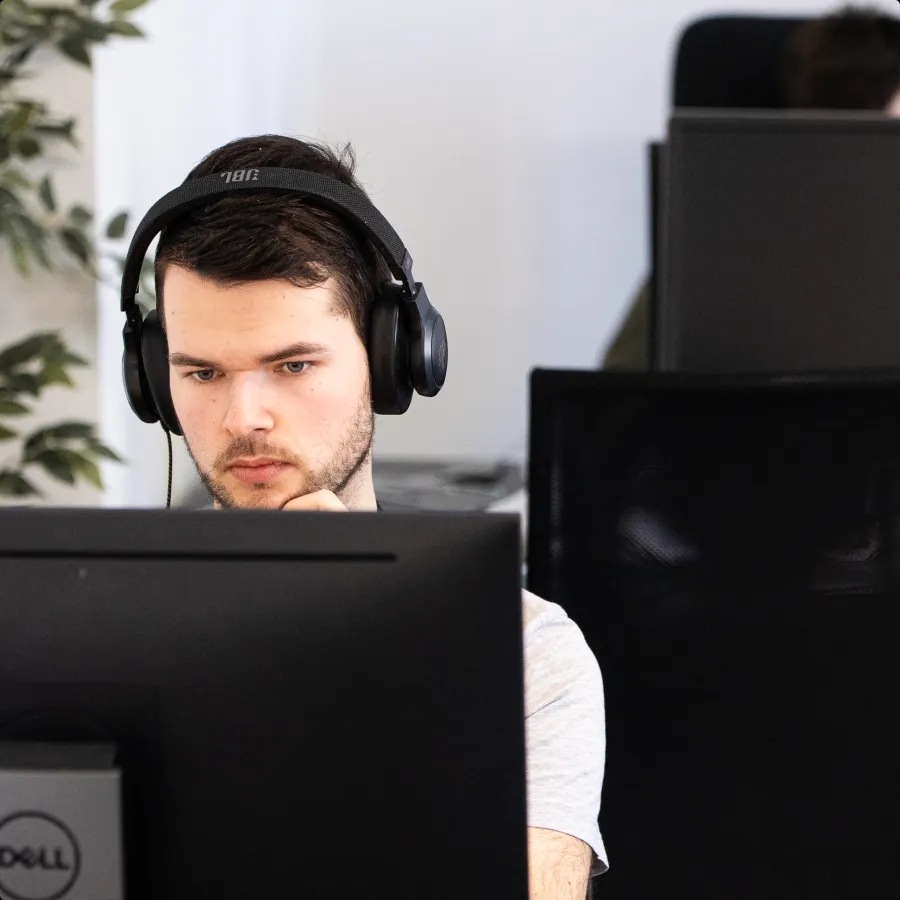 A QA engineer wearing headphones and looking at a computer monitor.