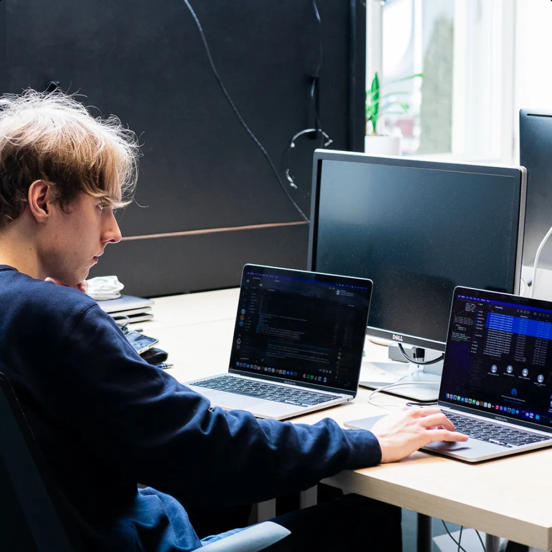Un ingeniero de control de calidad sentado en un escritorio y trabajando en una computadora portátil.