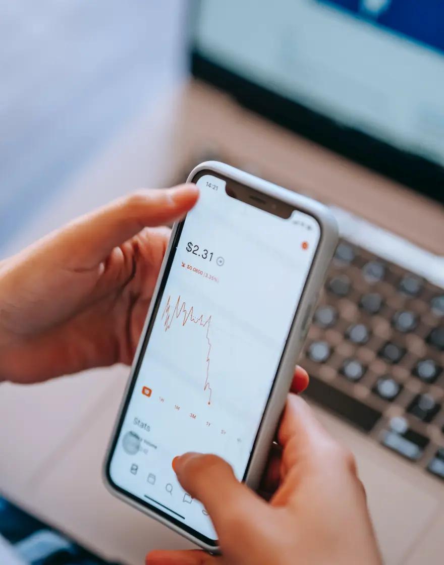 A person checking an investment balance and price chart in a mobile banking app