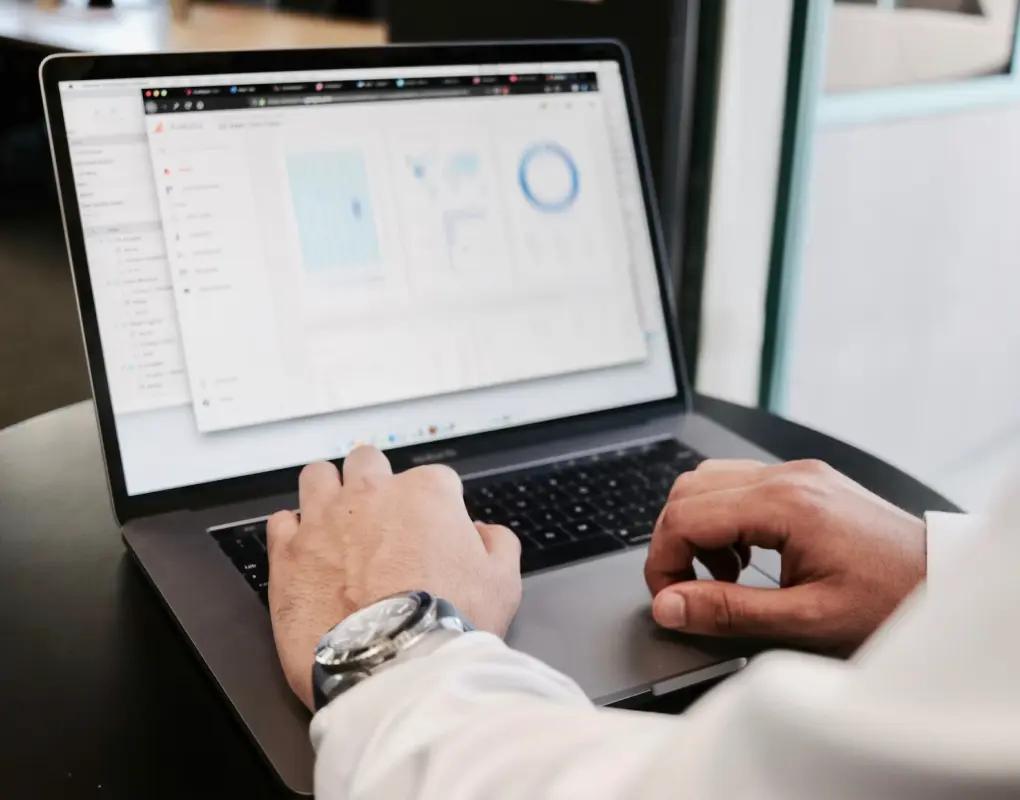 Hands typing on a laptop showing an analytics dashboard