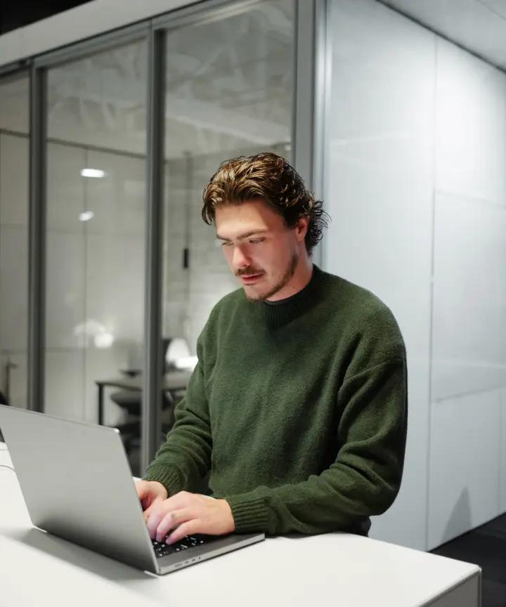 Software engineer reviewing code on a laptop in a modern office