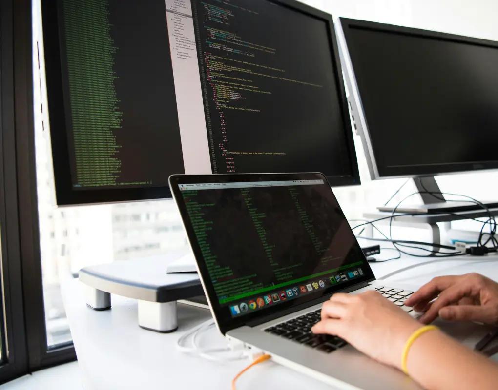 Developer working across a laptop and an external monitor of code