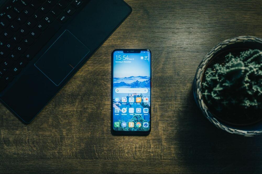 Android phone on a desk near a laptop and basket