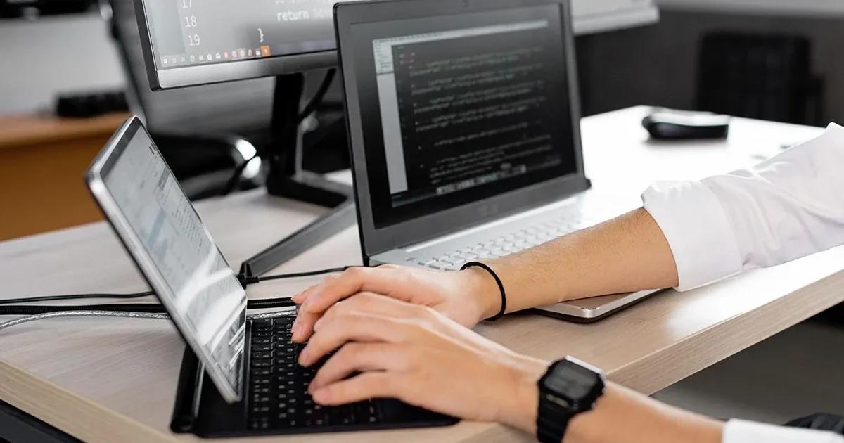 QA engineer working at a desk on multiple devices