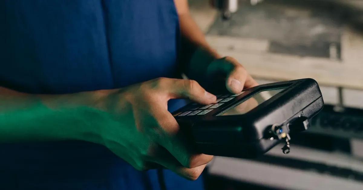 Person using a handheld industrial device with a touchscreen.
