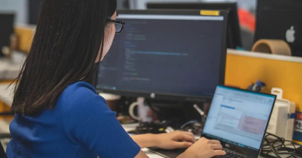 QA engineer testing logistics management software on laptop and desktop computer