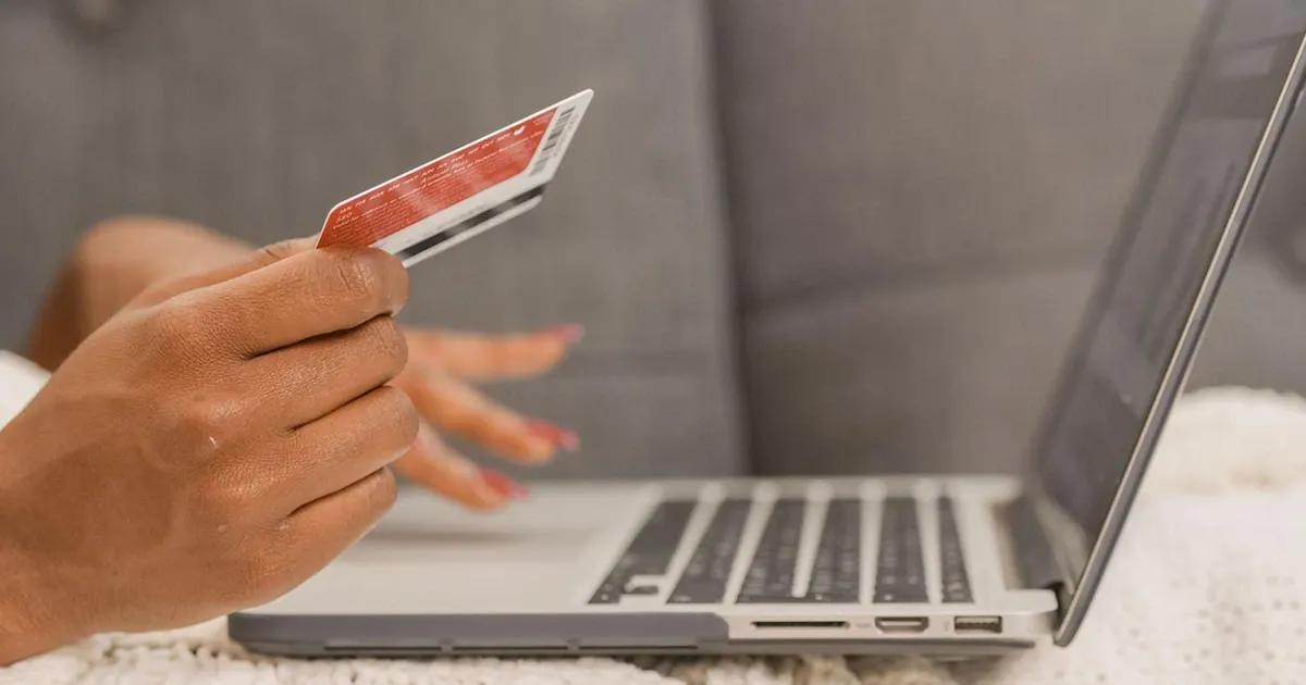 Person holding a credit card while using a laptop