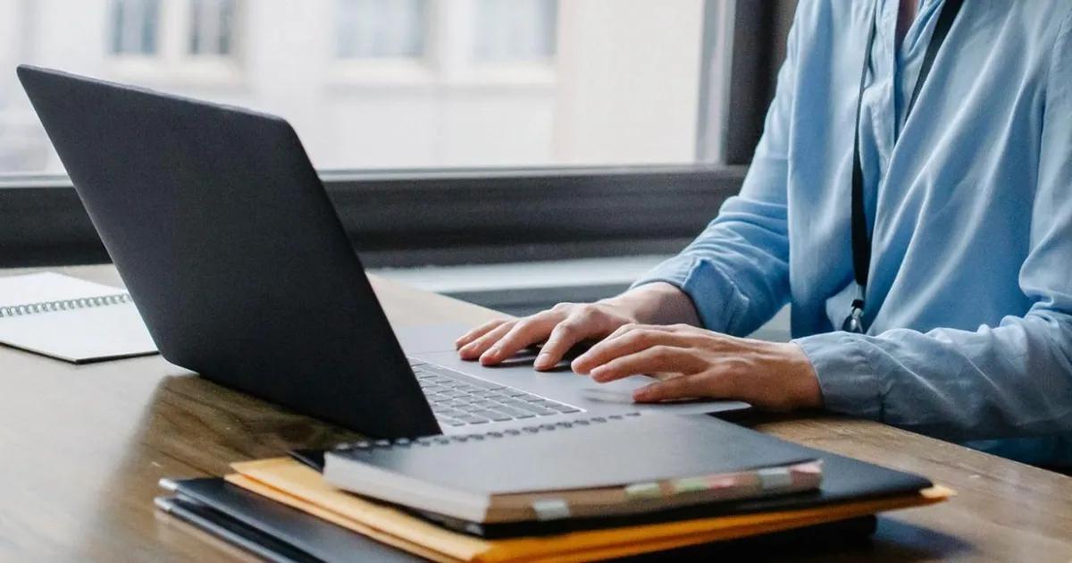 Person at a desk, typing on a laptop
